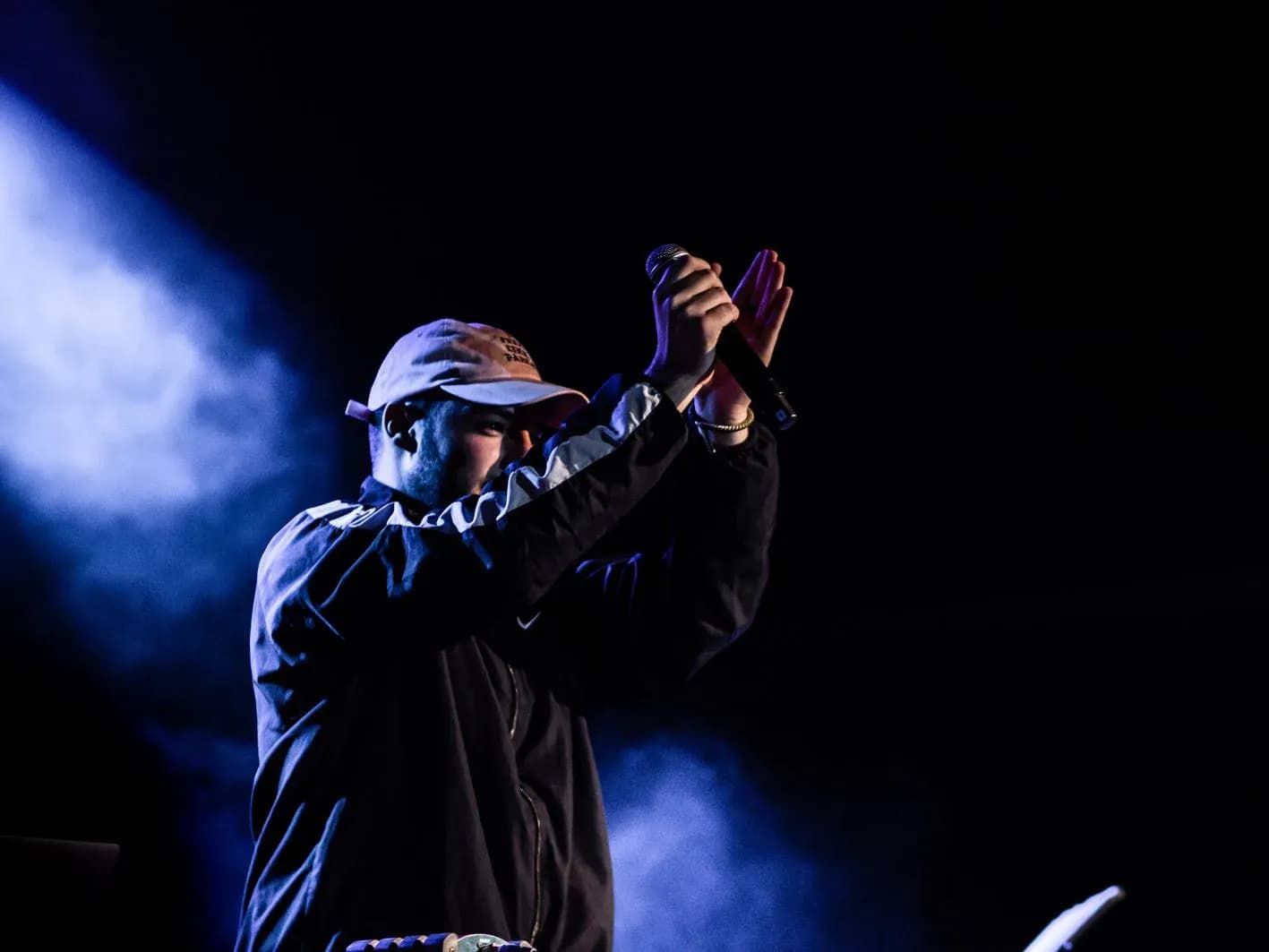 AkaEdu aplaudiendo con el micrófono en alto durante concierto, MC interactuando con el público en sesión de freestyle y dembow