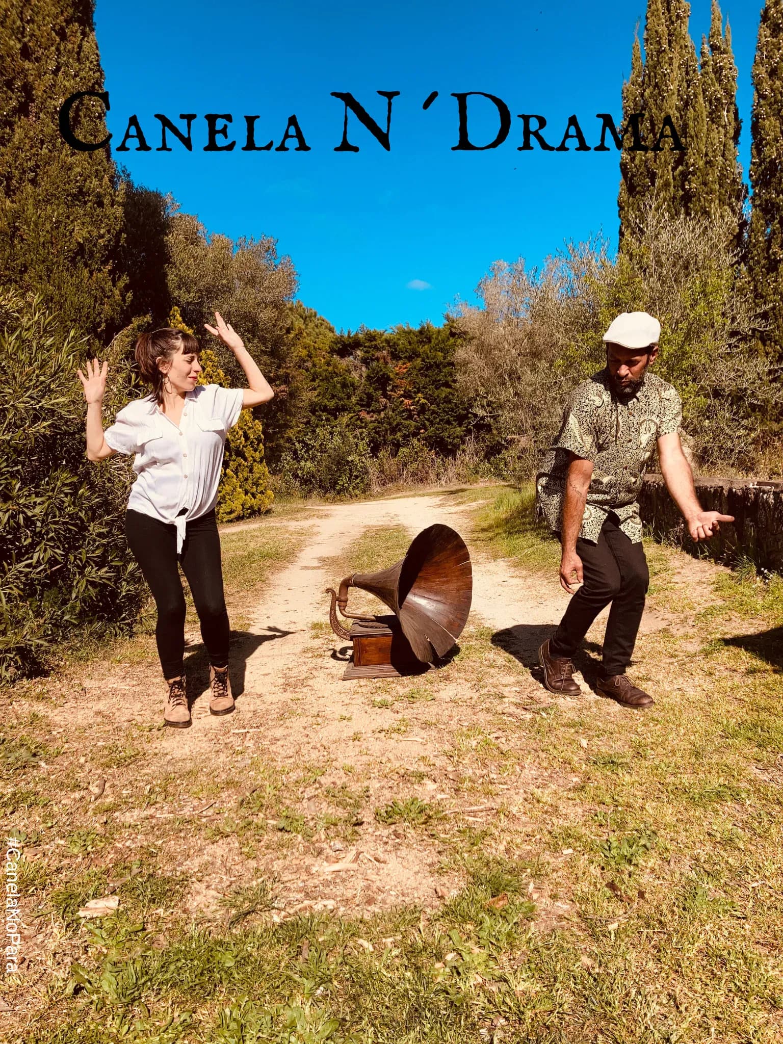 Duo Canela N Drama bailando junto a un gramofono antiguo en un camino entre cipreses