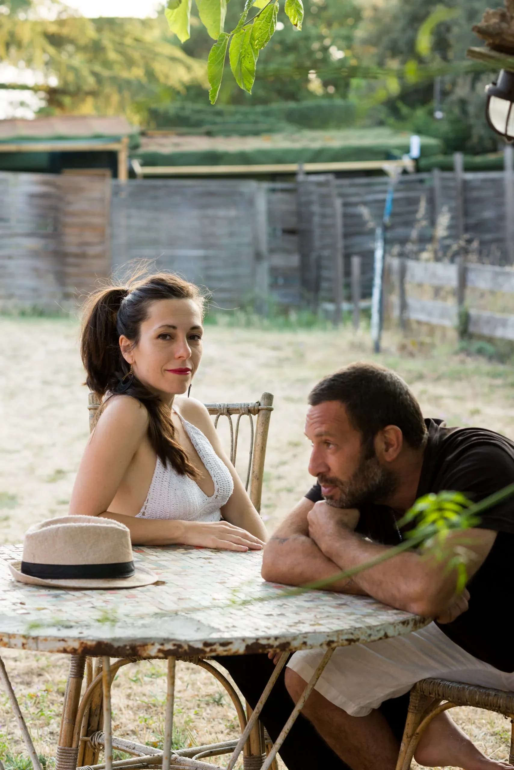 Yolanda Bretó y Alexis Bass de Canela N' Drama sentados a una mesa rural al atardecer, dúo acústico de versiones y temas propios
