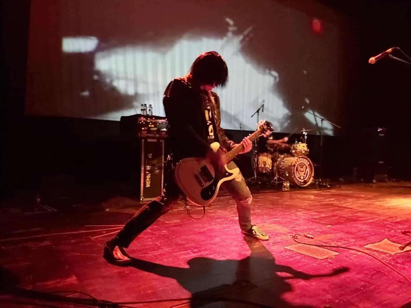 Cantante de Commando con micrófono, guitarrista y figura con máscara amarilla en directo de tributo a Ramones en sala