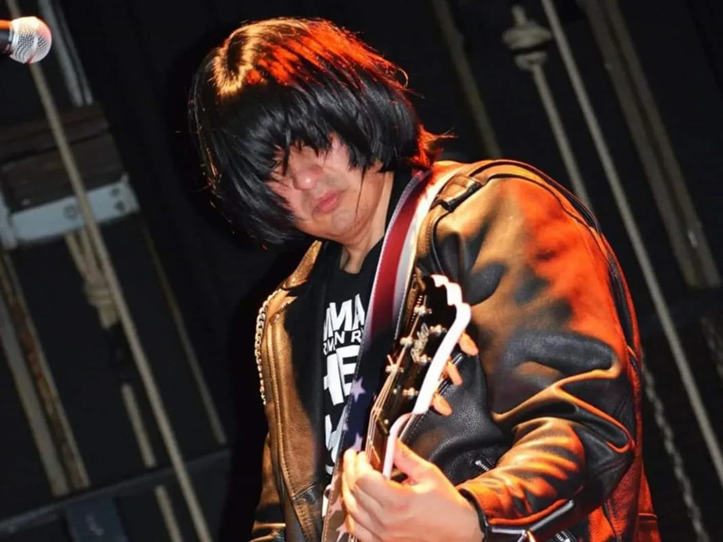 Vocalista de Commando gritando con micrófono, chupa de cuero y camiseta del tributo a Ramones, retrato en directo