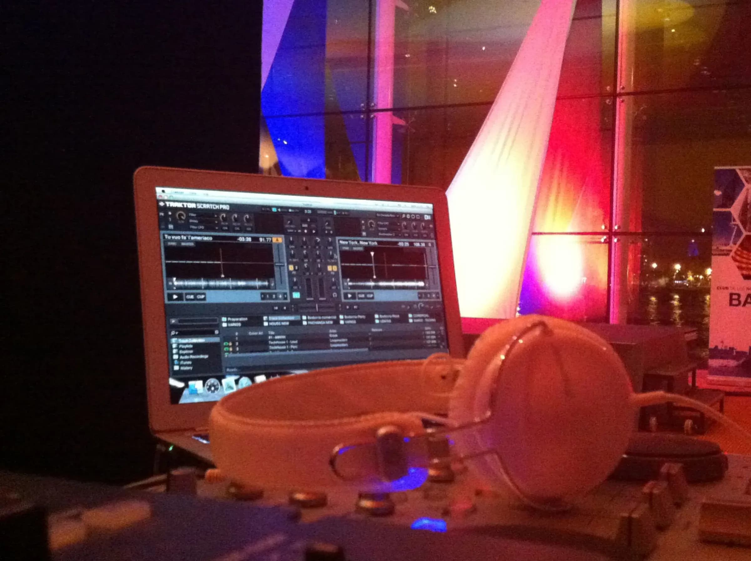 Cabina de discomovil con portatil corriendo Traktor Scratch y auriculares blancos junto a cortinas iluminadas