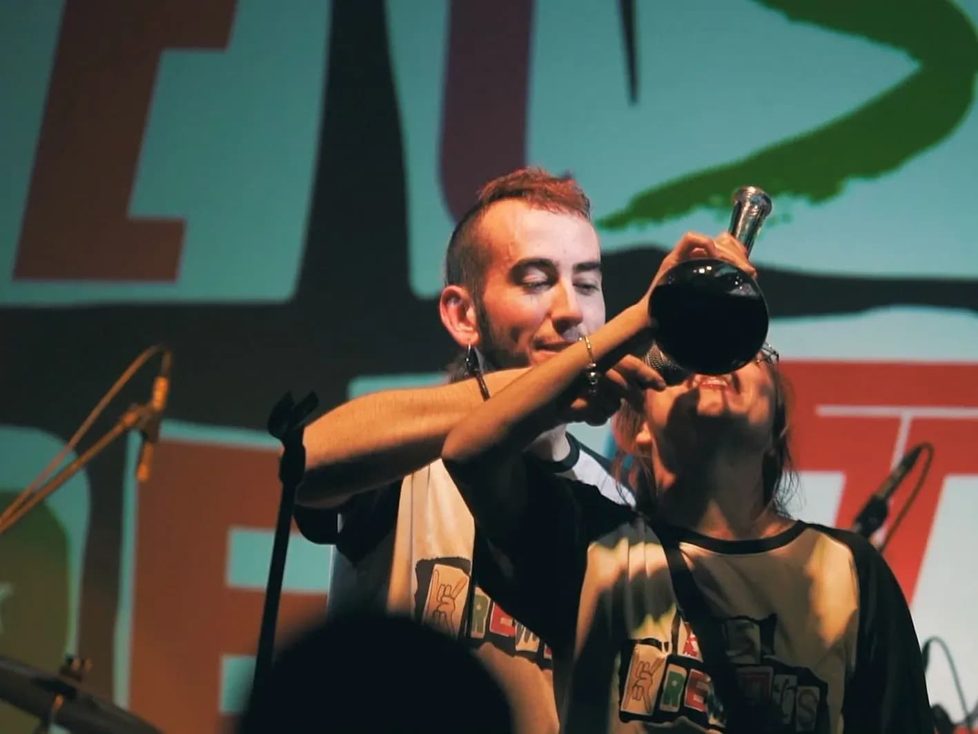 Guitarrista y bajista de Els Kremats bromeando con bocina y trompetilla en directo con camisetas estampadas del grupo