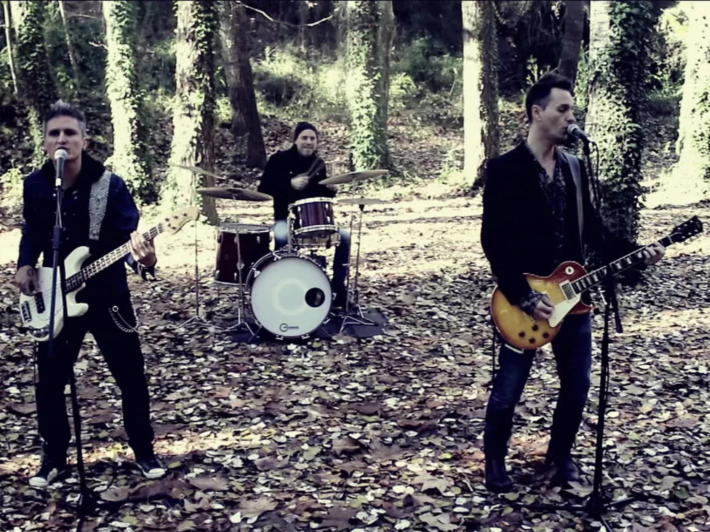 Mind Trick tocando en directo en un bosque con batería y guitarras eléctricas entre árboles, sesión de versiones acústicas