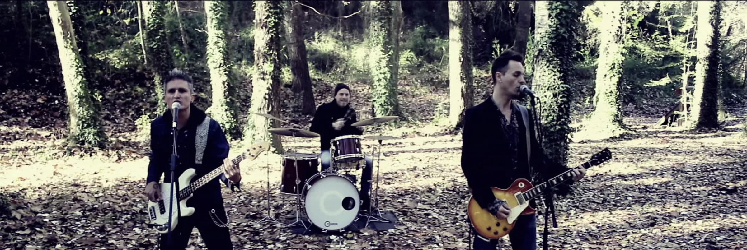 Mind Trick tocando en directo en bosque con bateria y dos guitarristas entre arboles y luz natural difusa
