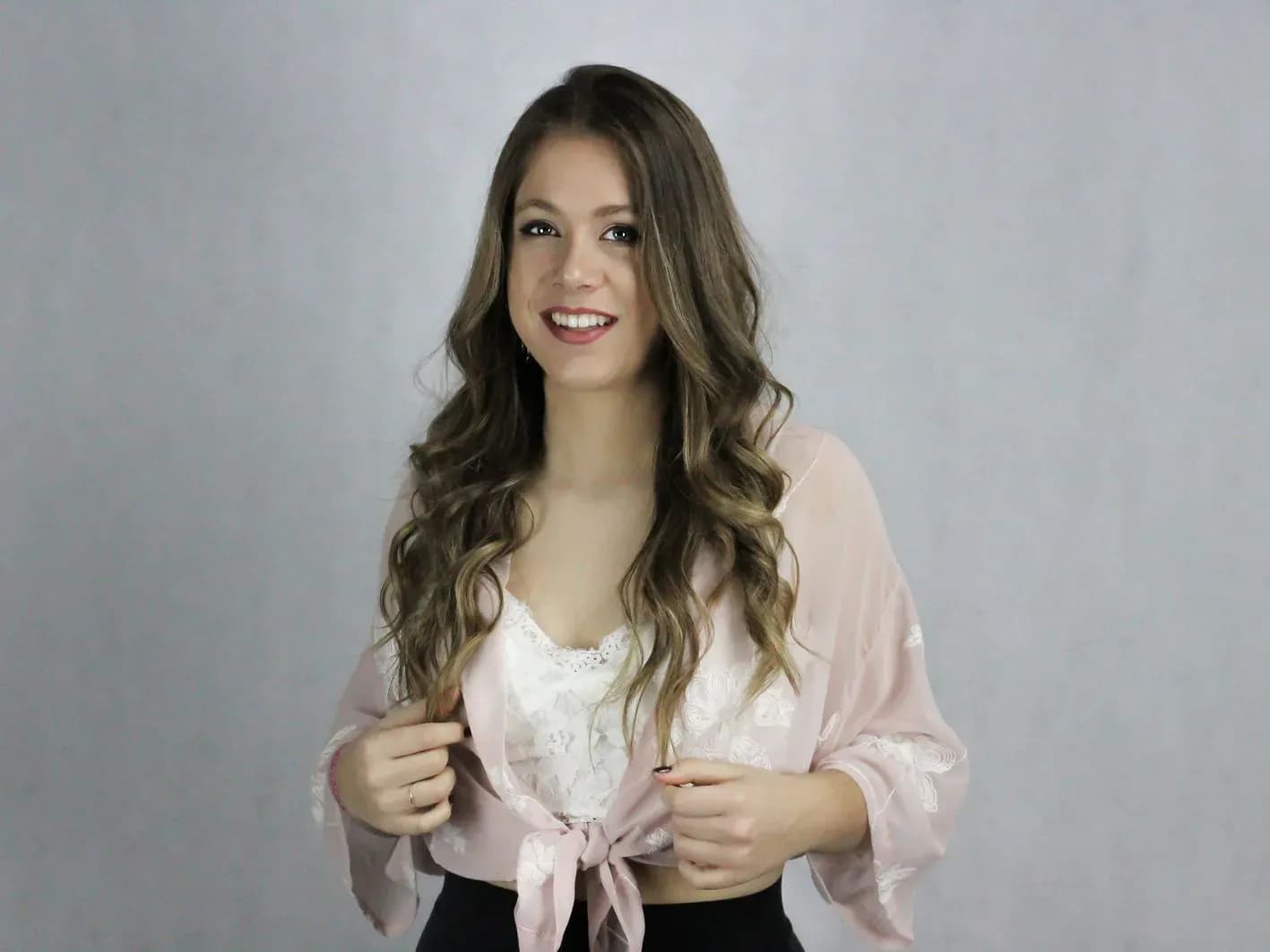 Retrato en estudio de Mireia DG con kimono rosa y top de encaje blanco, sesión promocional sobre fondo gris claro