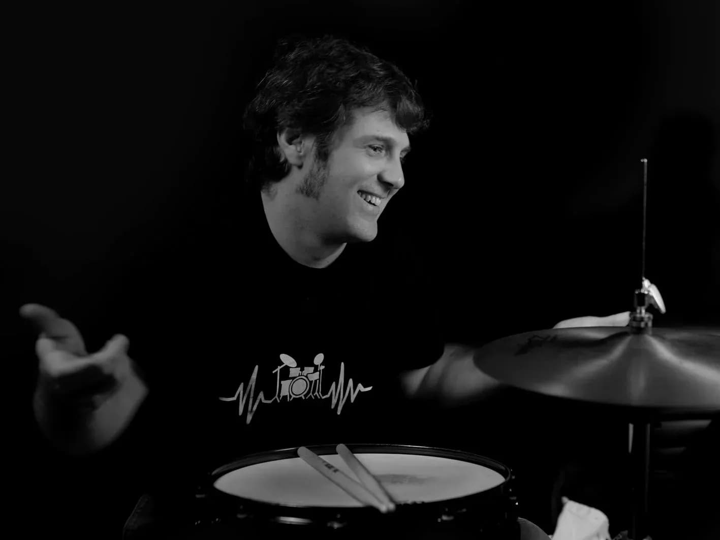 Batería de Movie Band sonriente tras la caja y los platillos en sesión de retrato en blanco y negro de estudio