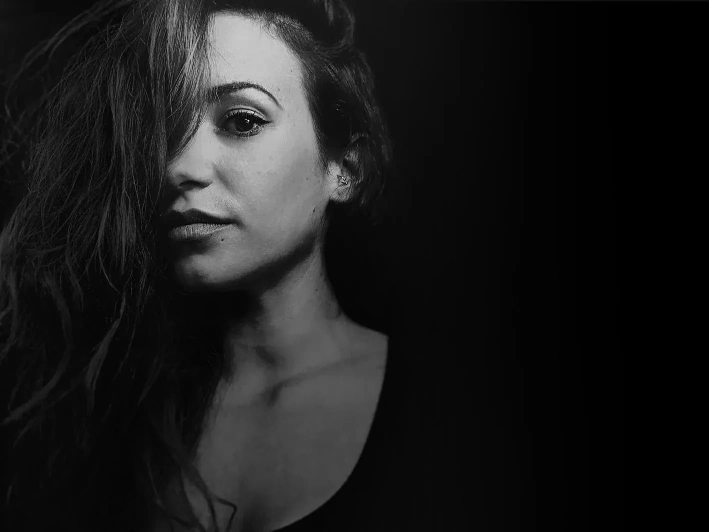 Vocalista de Movie Band con melena rizada en retrato lateral en blanco y negro sobre fondo oscuro de estudio