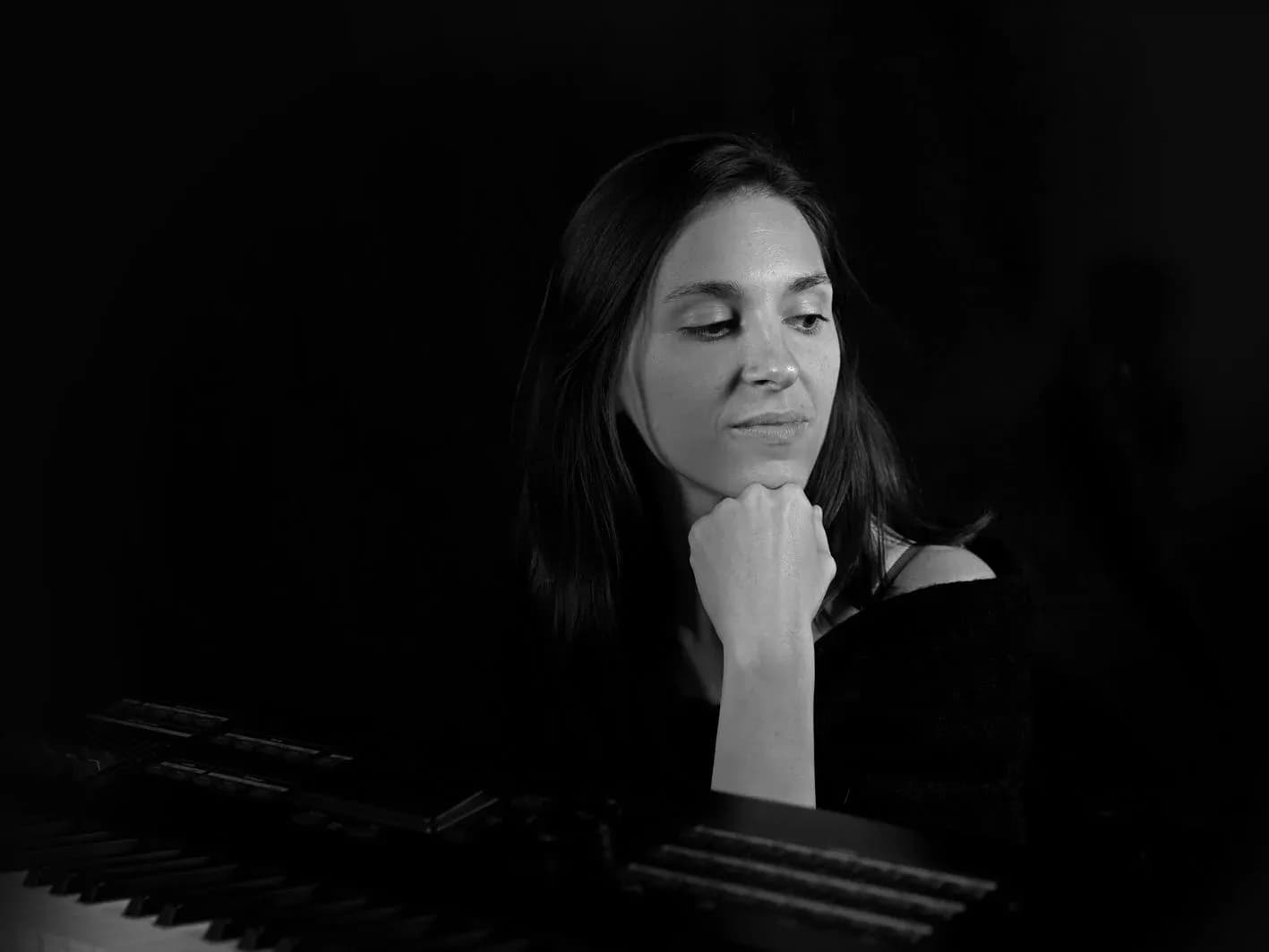 Pianista de Movie Band con melena larga y mano en la barbilla apoyada en el piano, retrato en blanco y negro
