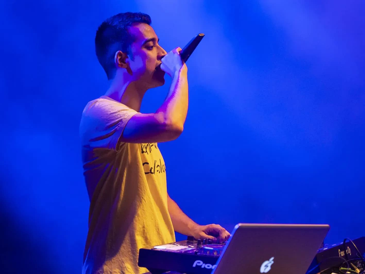 Quim Martinez cantando al microfono junto a la controladora Pioneer iluminado por luces azules