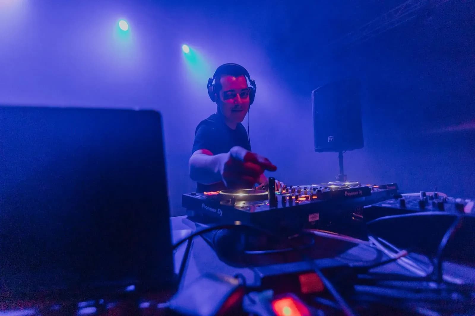 Quim Martinez tras los platos Pioneer DJ con auriculares y camiseta negra entre humo y luces azules