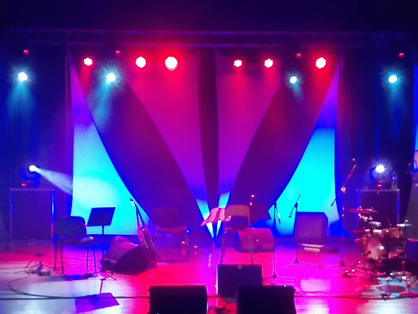 Escenario montado con sonorizacion e iluminacion en azules y rojos antes de un concierto