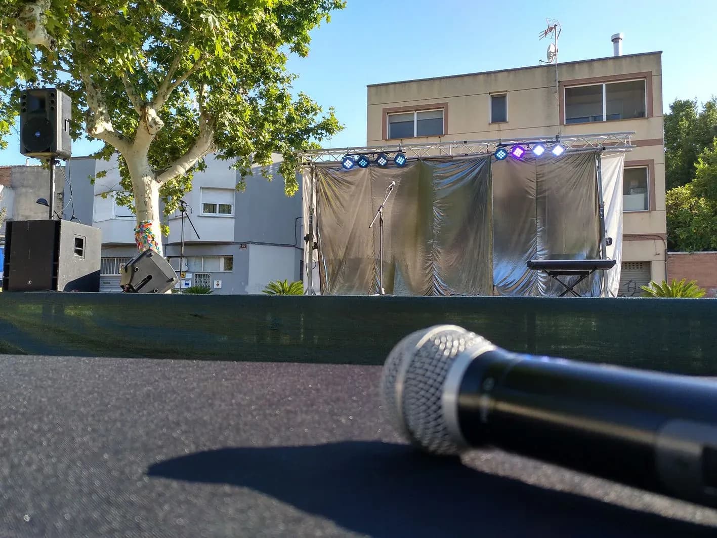 Escenario montado en plaza con sonorizacion iluminacion truss y microfono en primer plano antes del evento