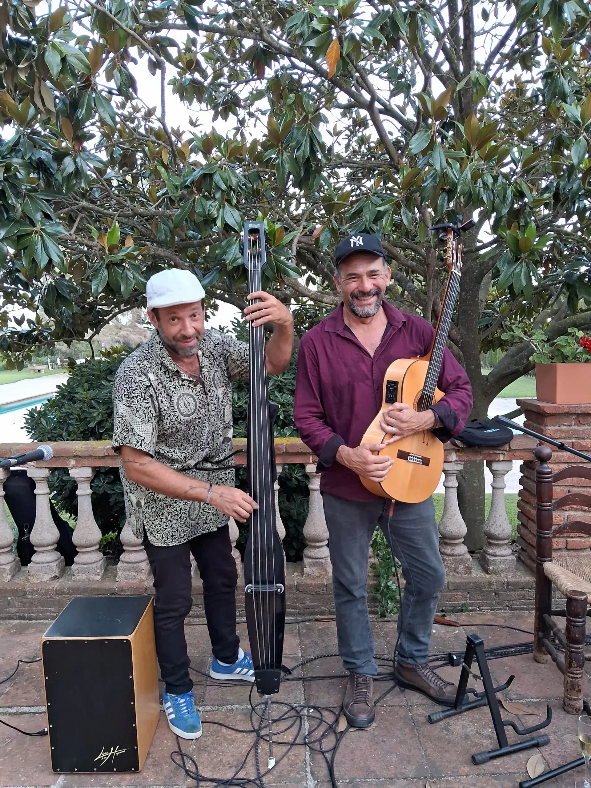 Dúo Barreto y Cía posando sonrientes con contrabajo eléctrico y guitarra clásica junto a piscina, formato acústico para eventos
