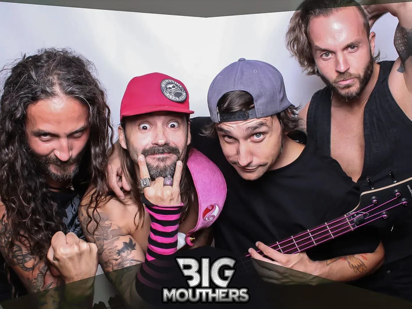 Los cuatro integrantes de Big Mouthers posando juntos en photocall con gorras y actitud rockera ante el logo de la banda