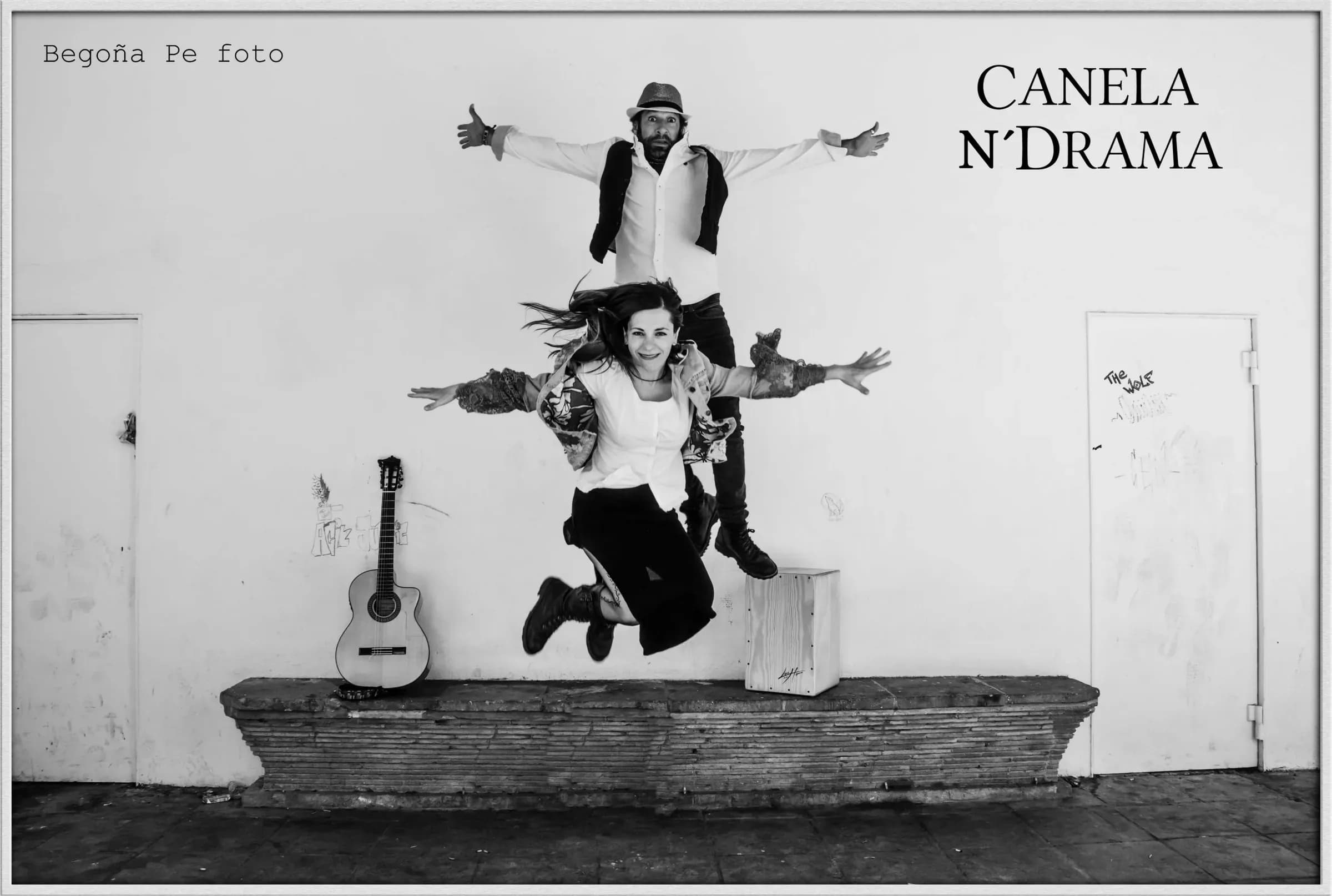 Yolanda Bretó y Alexis Bass de Canela N' Drama saltando juntos en blanco y negro junto a guitarra y cajón flamenco