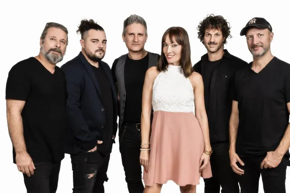 Banda Miris Way al completo con Míriam Hernández en vestido blanco y rosa rodeada de cinco músicos sobre fondo blanco