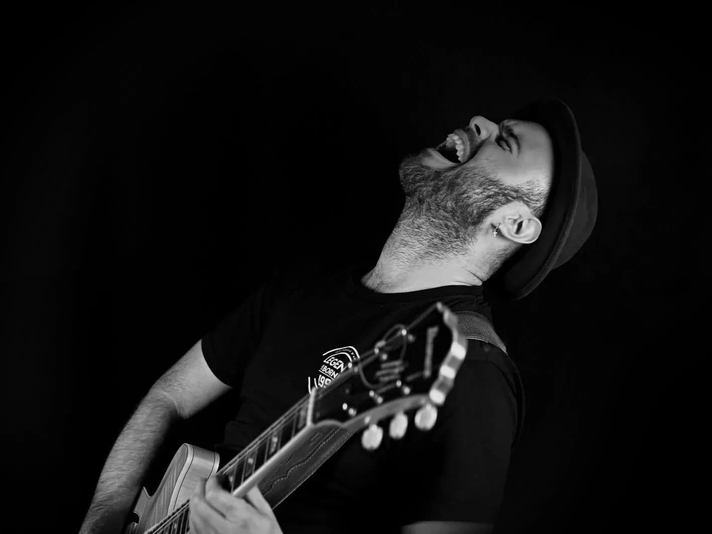 Guitarrista de Movie Band con sombrero gritando con la cabeza hacia atrás tocando una Les Paul en sesión de estudio